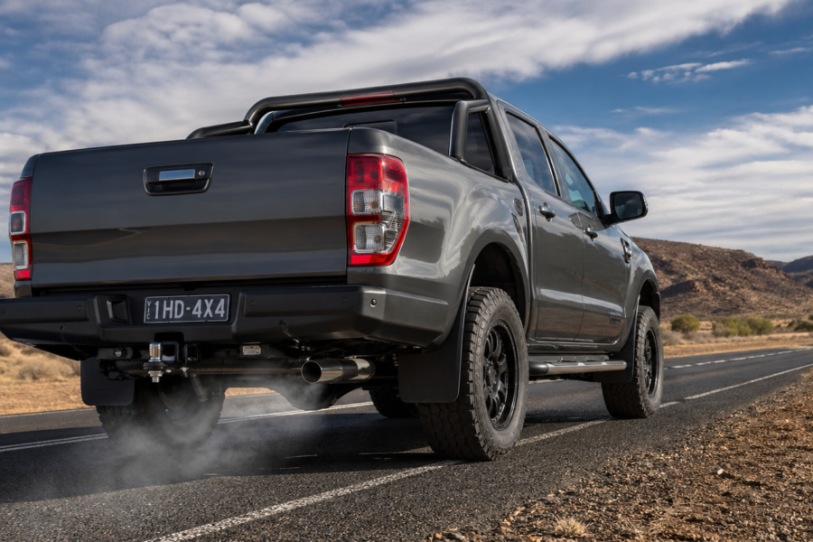 A grey 4x4 pickup truck driving on an open road emitting smoke from the tailpipe, highlighting the importance of efficient diesel exhaust flow-willys workshop