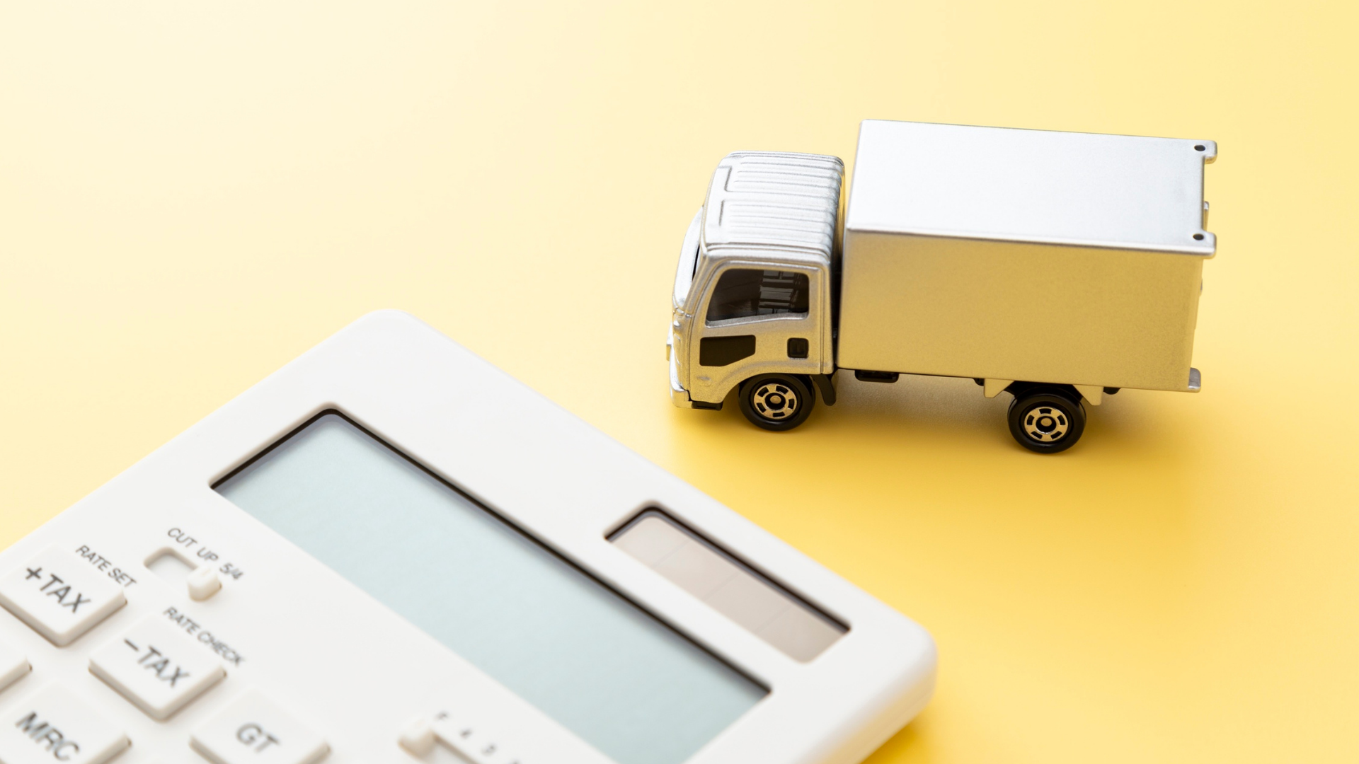 Small white delivery truck next to a calculator on a yellow background, symbolising turbo upgrade expenses.